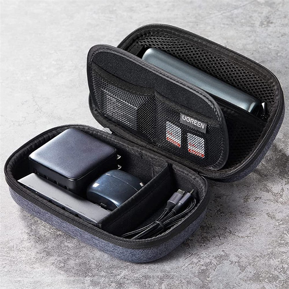 The organiser open on stone, holding a power bank, a charger, a cable and memory cards in its mesh pockets