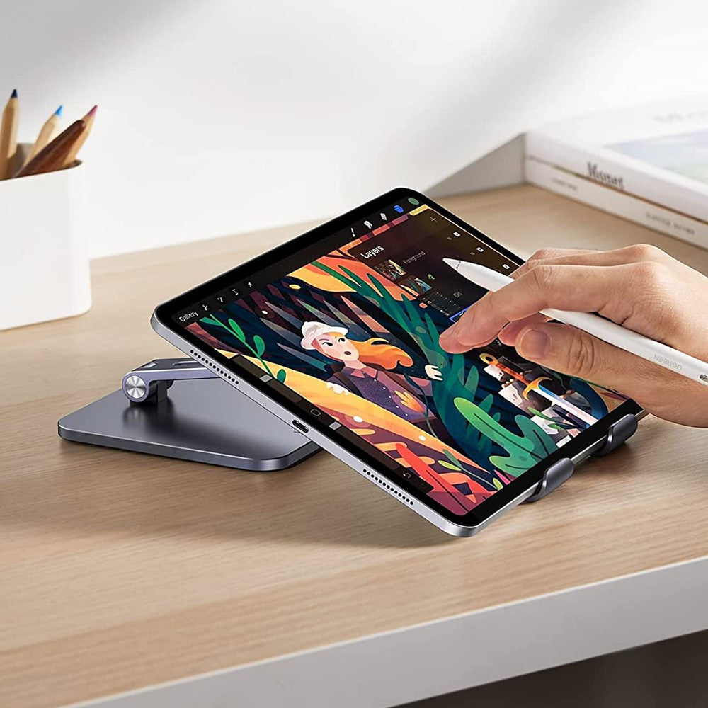 Someone drawing on an iPad held at a low angle on the stand with a stylus