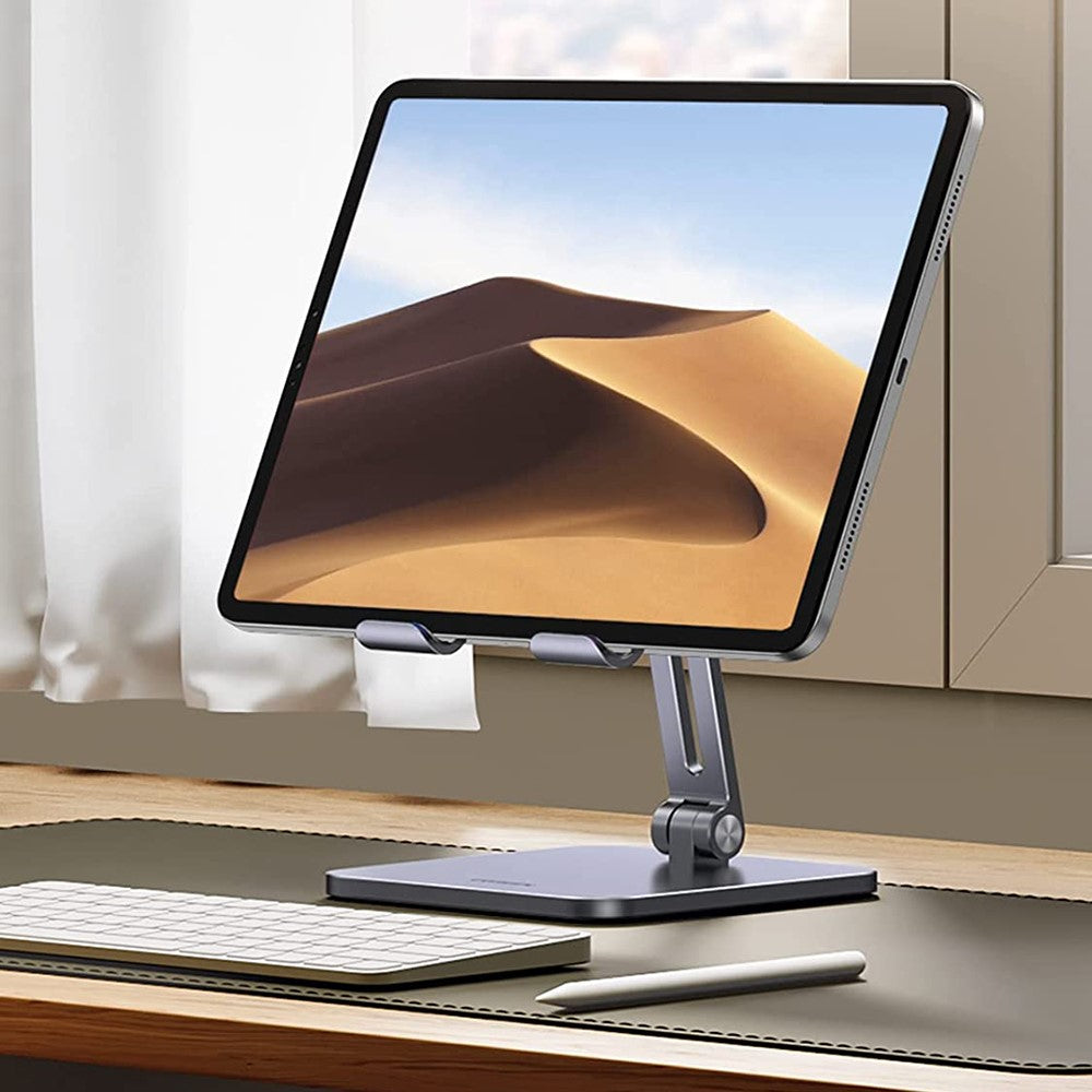 The stand holding a tablet upright beside a keyboard on a desk by a window