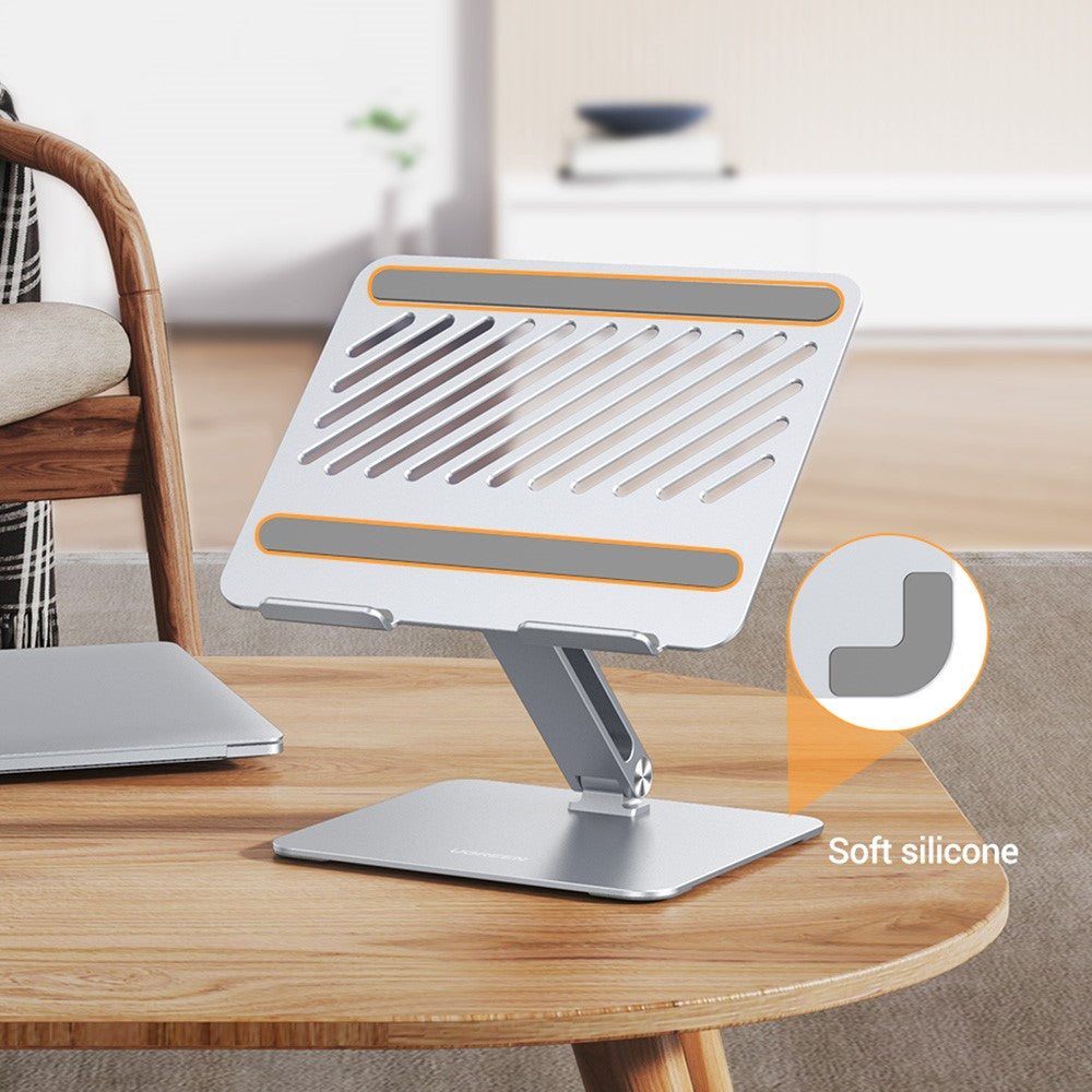 The stand on a round table with a closed laptop, highlighting the soft silicone contact pad