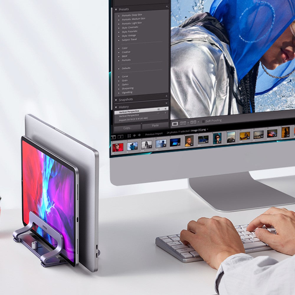 The stand holding a laptop and a tablet on edge beside a desktop monitor while someone types