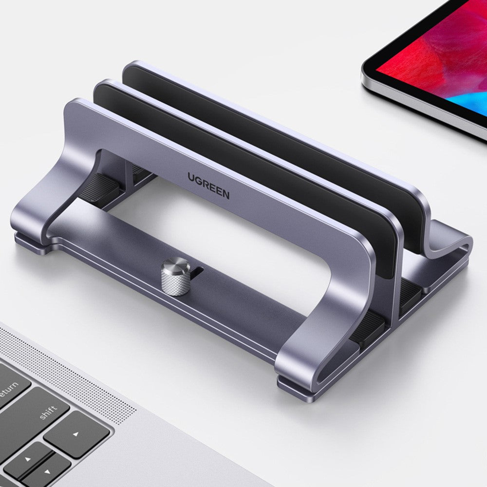The stand photographed beside a laptop keyboard, showing its twin slots and adjustment screw