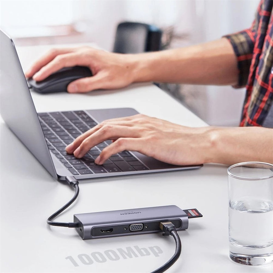 A person working on a laptop with the dock beside it and an Ethernet cable attached, captioned 1000Mbps