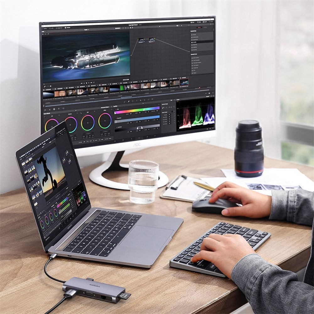 A video editing setup with a large monitor, a laptop and a camera, all connected through the dock