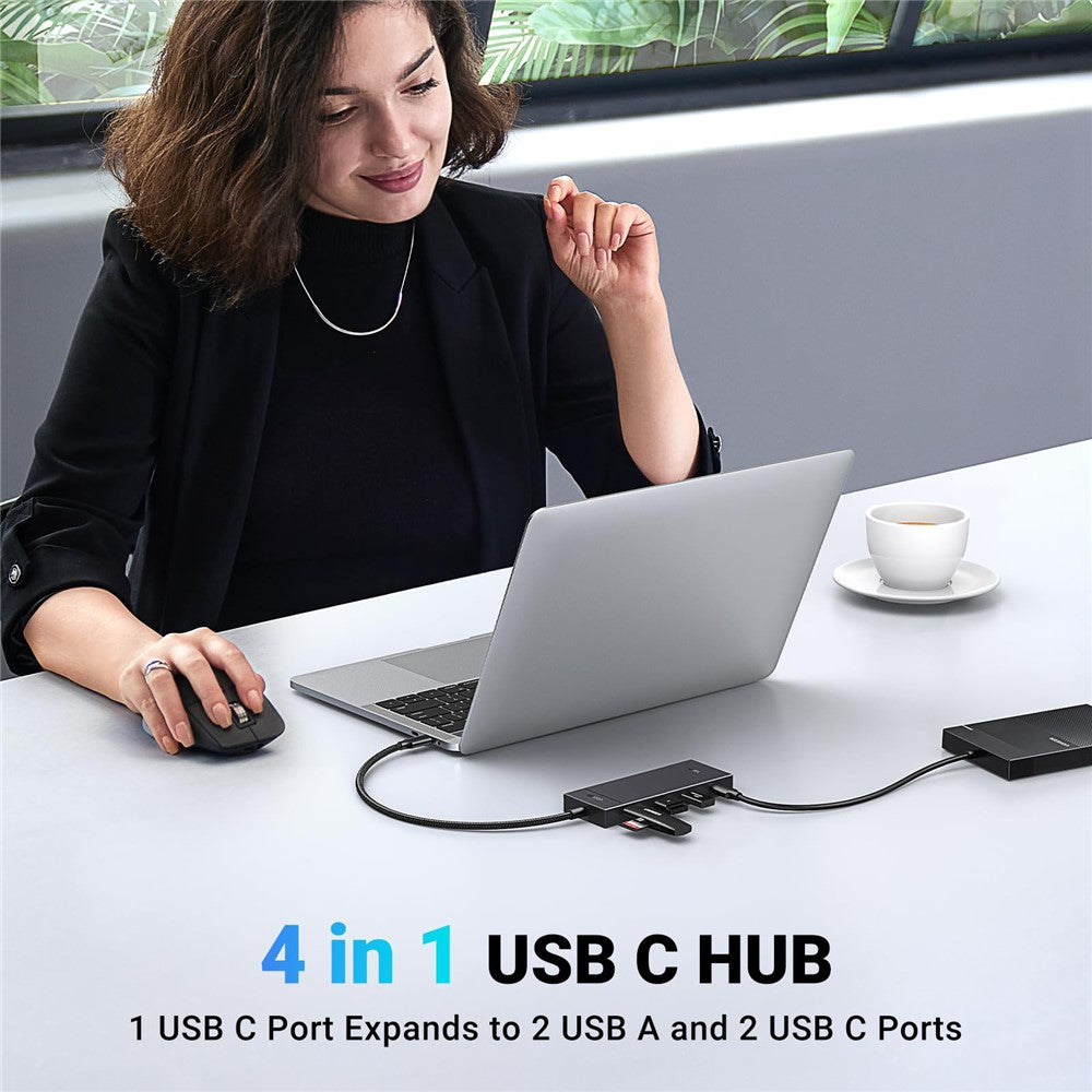 A woman at a cafe table using a laptop with the hub connected, captioned one USB-C port expands to two USB-A and two USB-C