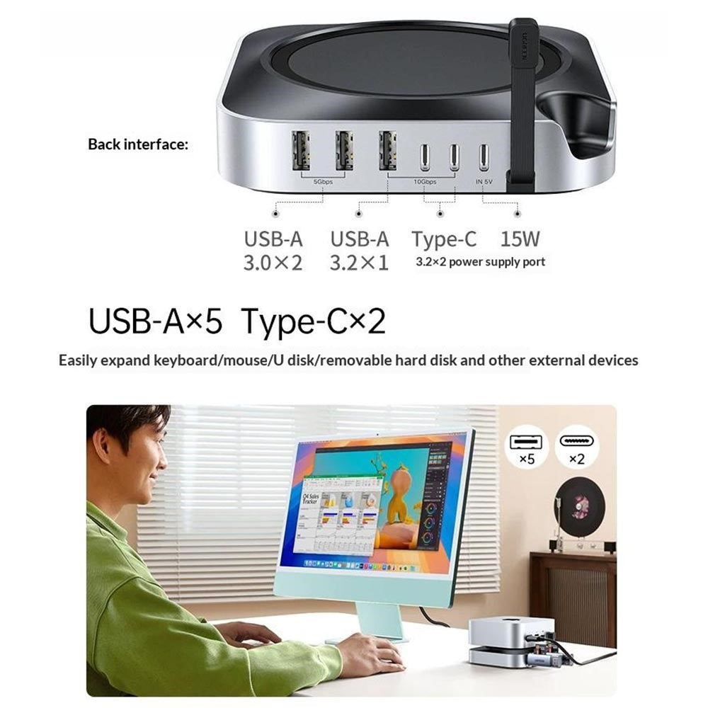 The rear interface labelled with five USB-A and two USB-C ports, above a person working at a Mac with the dock beneath it