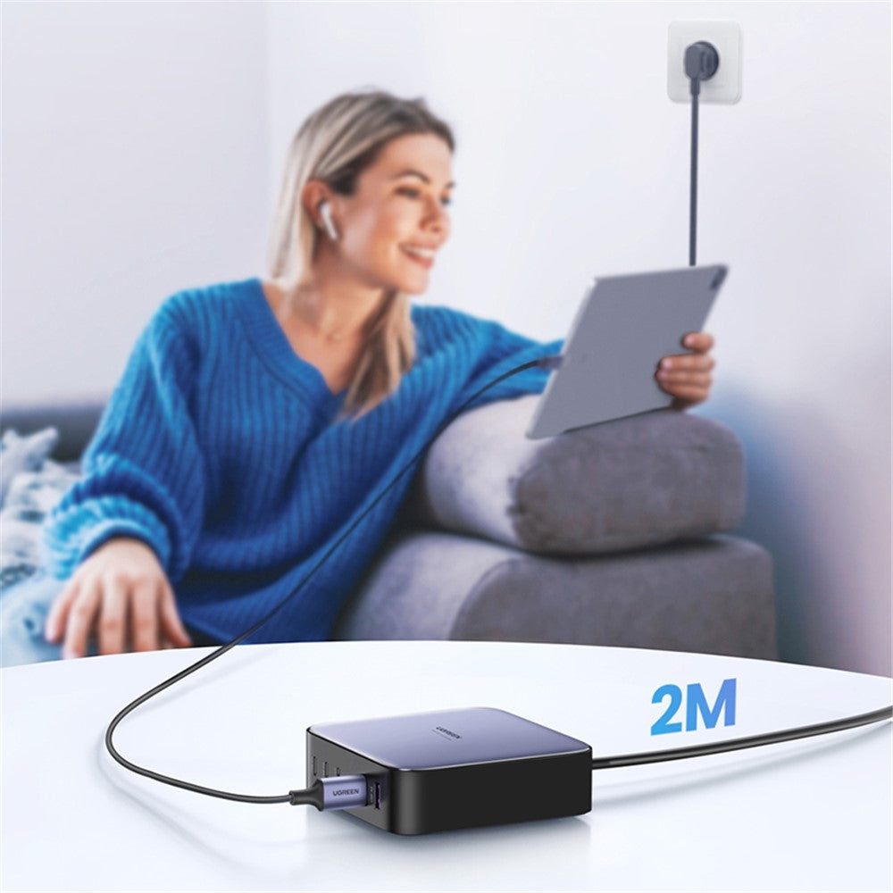 A woman on a sofa using a tablet, with the charger on a table and its 2 m cord running to a wall socket