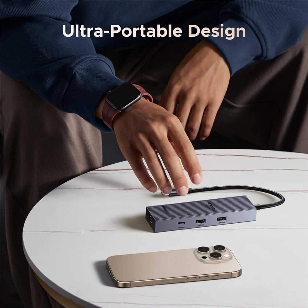 A person setting the palm-sized UGREEN hub on a round table beside an iPhone