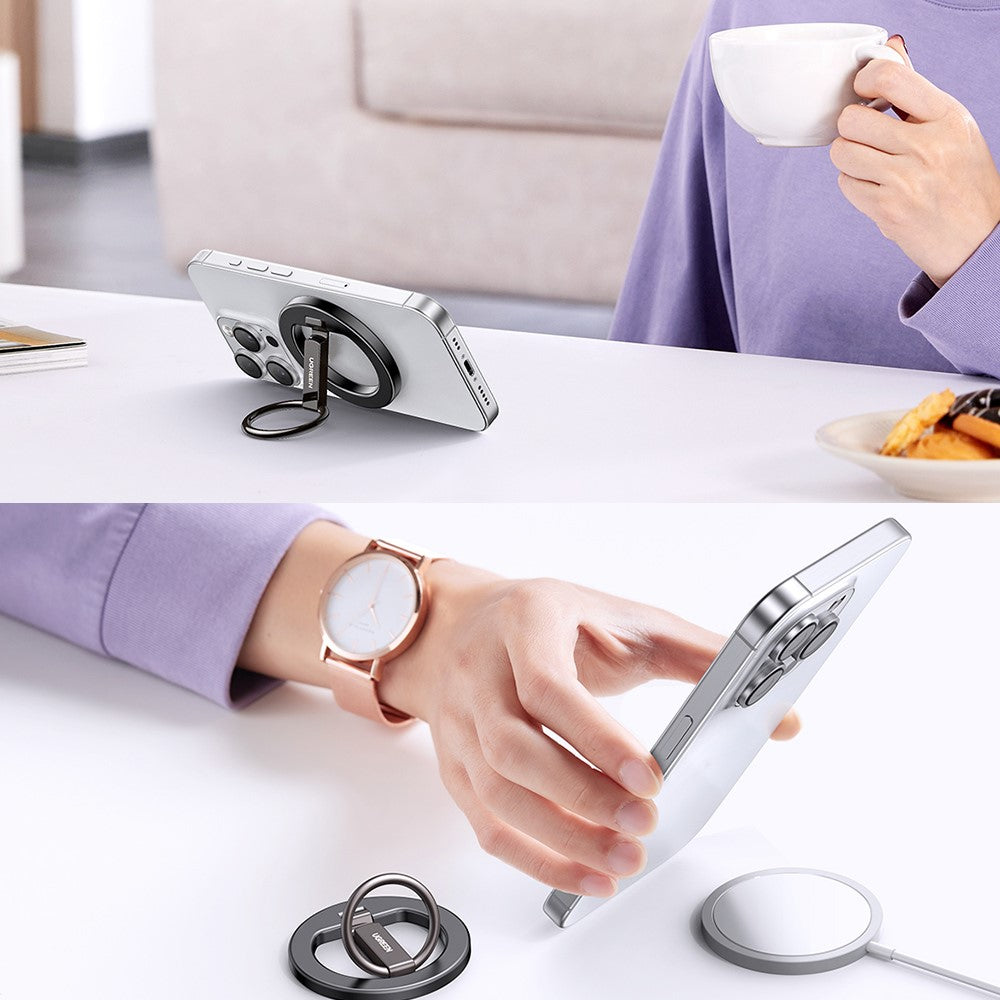 A person drinking coffee beside a propped-up phone, and using the ring as a finger loop while holding the phone
